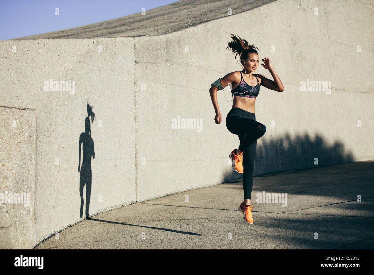 Fitness woman doing cardio interval training outdoors. Caucasian female in sportswear exercising outdoors in morning. Stock Photo