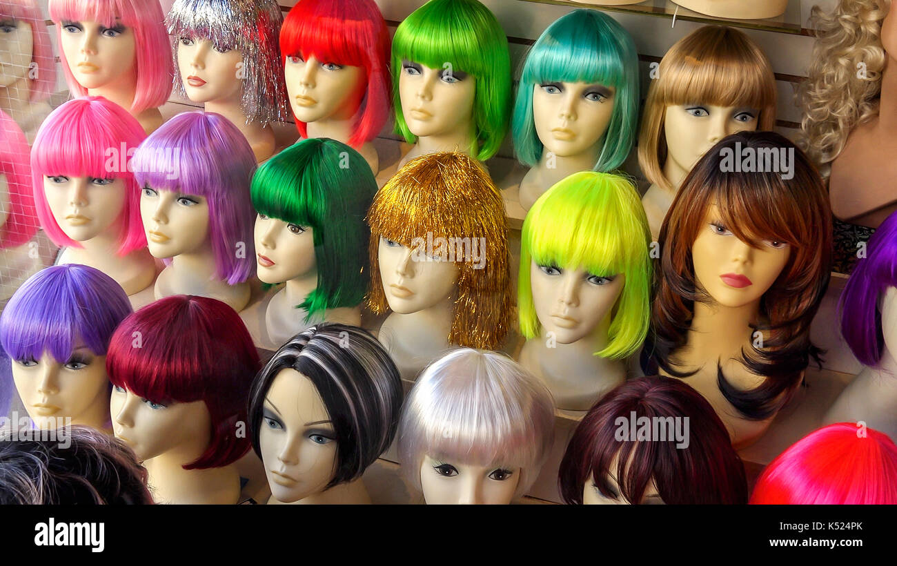 Mannequins wearing colorful wigs in a wig shop store window Stock Photo