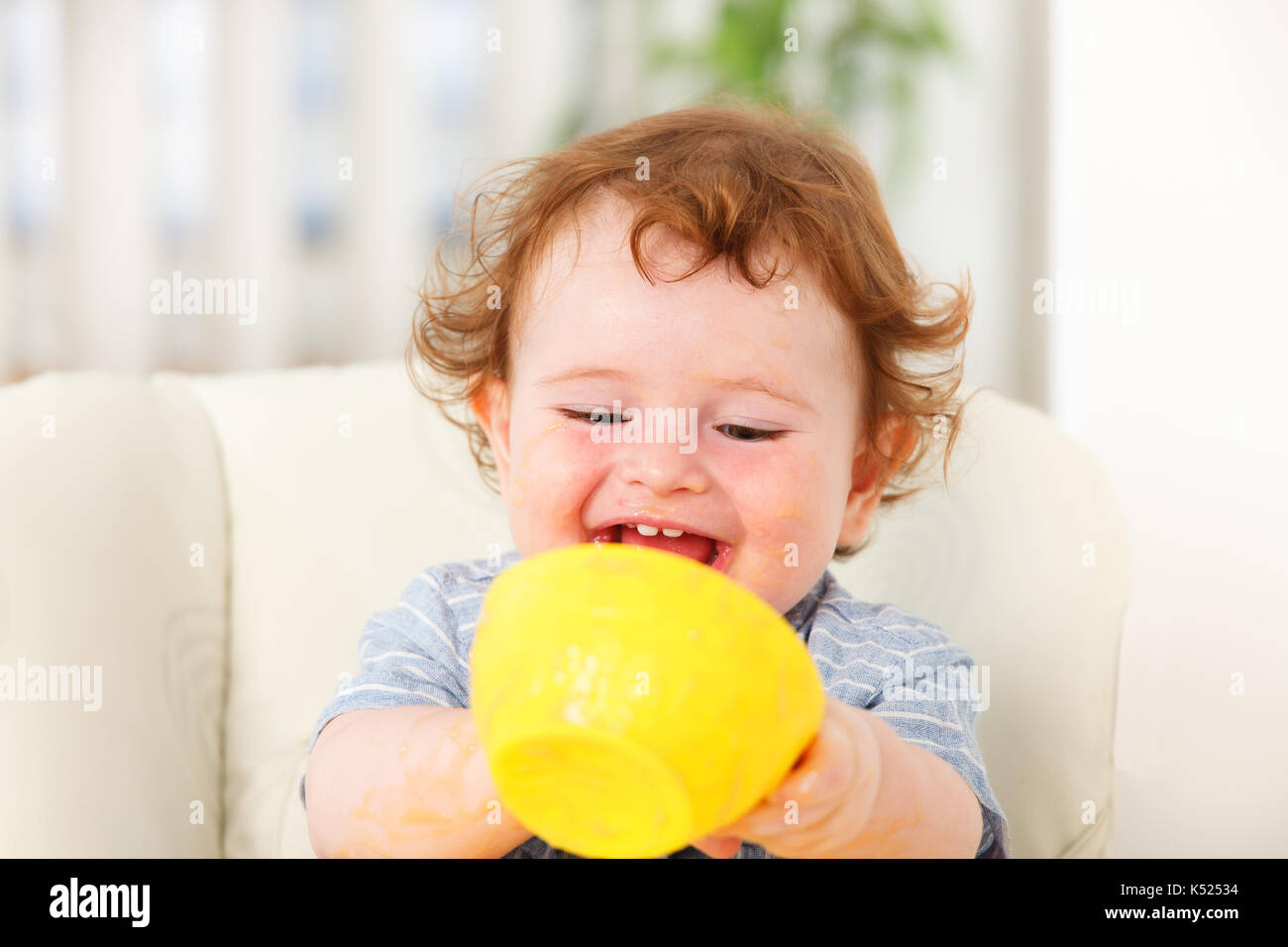 Cute baby boy eating by himself on high chair Stock Photo