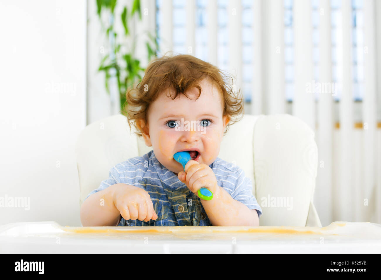 Cute baby boy eating by himself Stock Photo