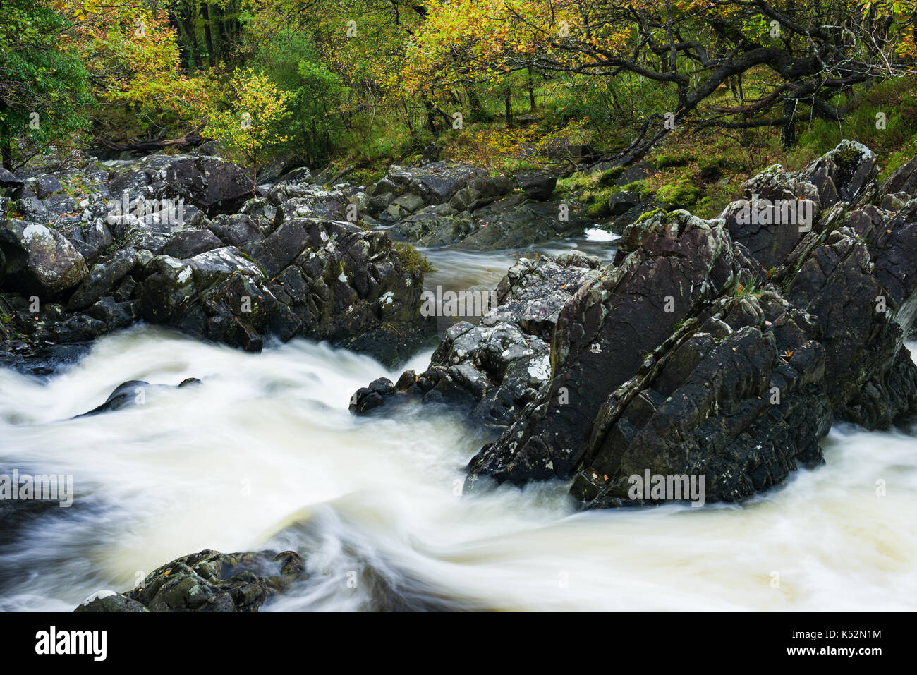 River running through rocks and Autumn coloured trees, Wales, United Kingdom Stock Photo
