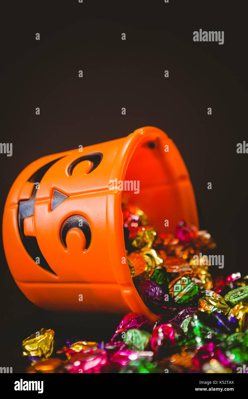 Orange bucket with colorful chocolates during Halloween over black background Stock Photo