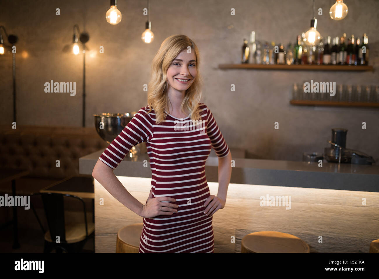 Portrait of beautiful woman standing with hands on hip at counter in resturant Stock Photo