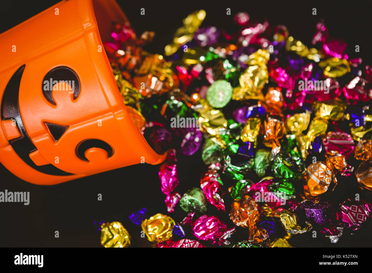 High angle view of bucket with colorful chocolates during Halloween over black background Stock Photo