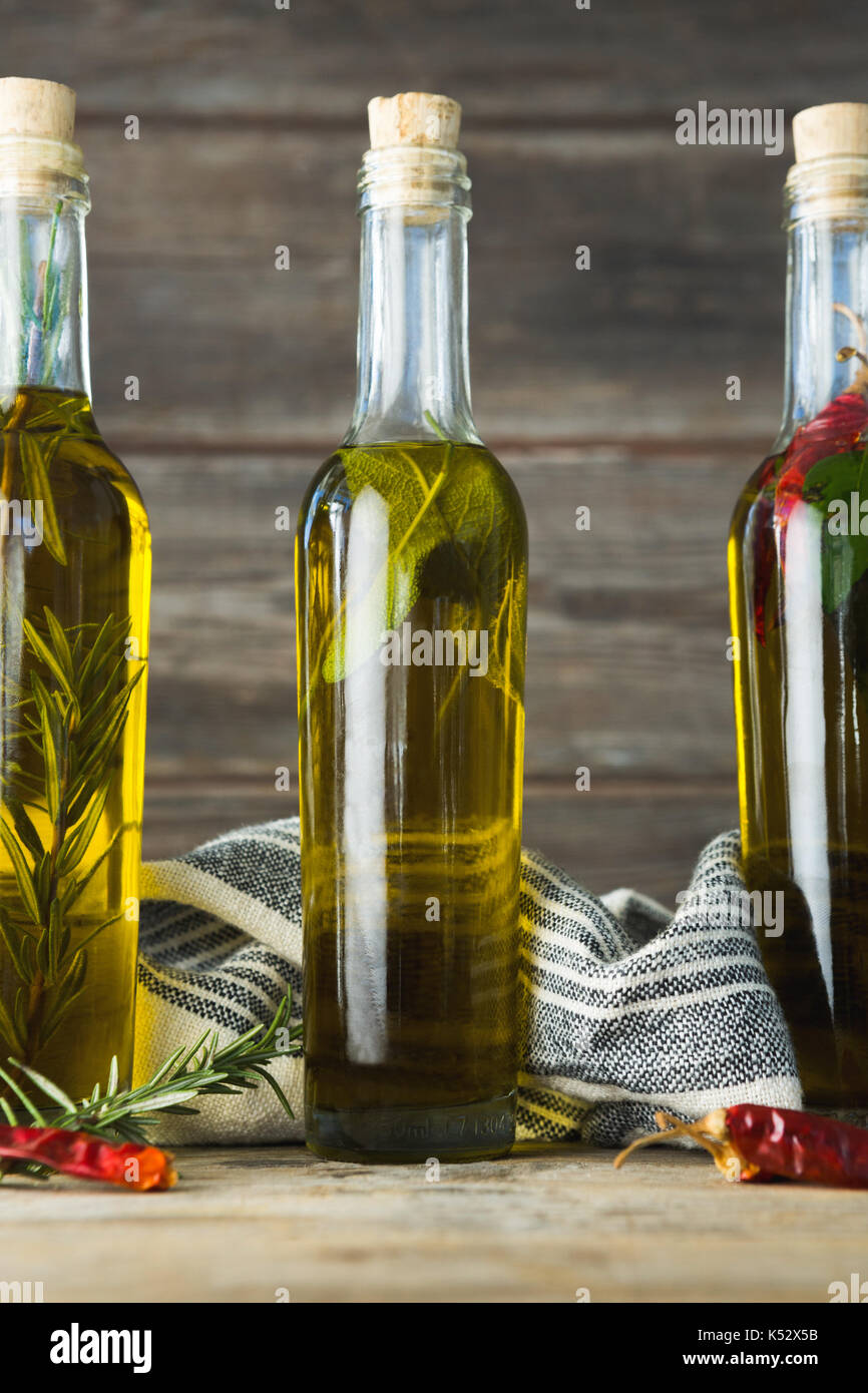 Olive oil bottles with herbal and spices against wooden background Stock Photo