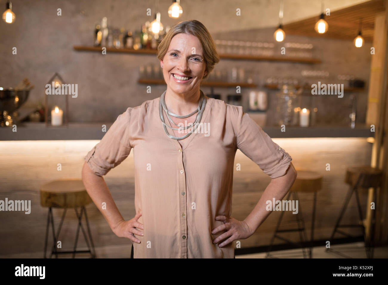 Portrait of beautiful woman standing with hands on hip in restaurant Stock Photo