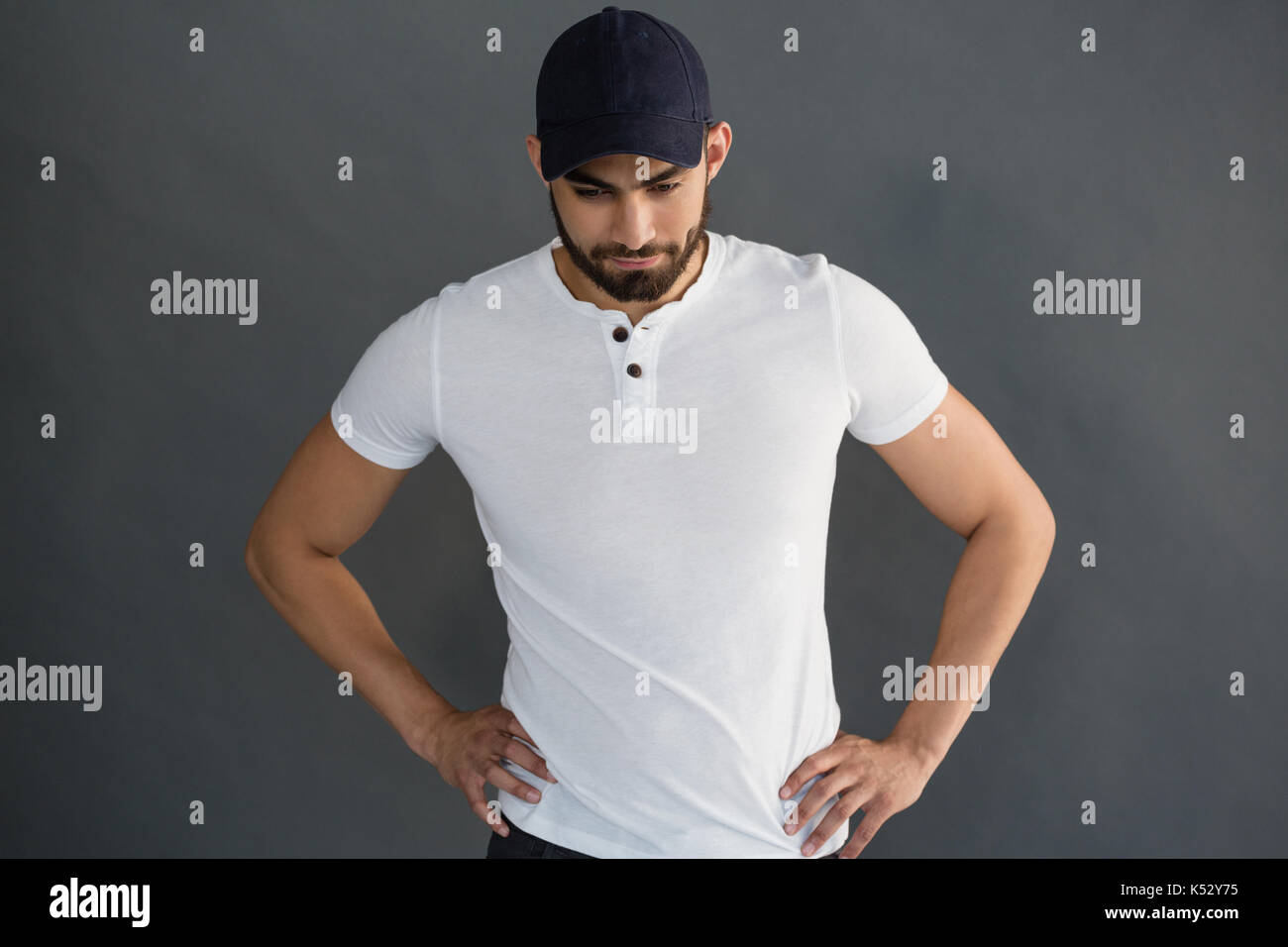 Handsome man posing with hand on hip against grey background Stock Photo