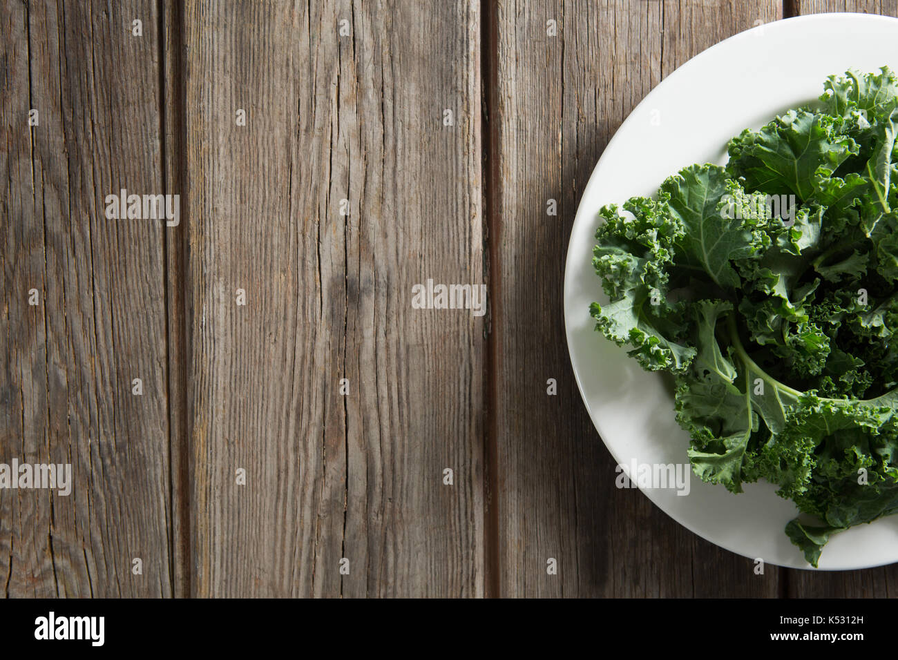 Overhead view of fresh kale vegetable in plate on wooden table Stock Photo