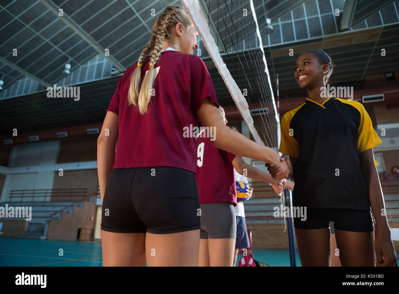 Smiling female players shaking hands after match in the volleyball