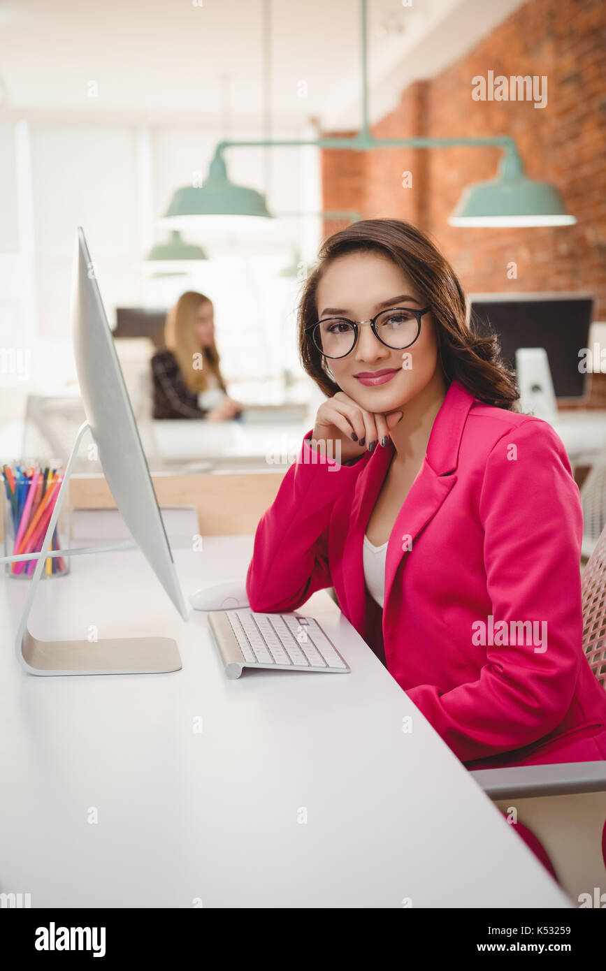 Portrait of smiling female executive sitting at desk in office Stock ...