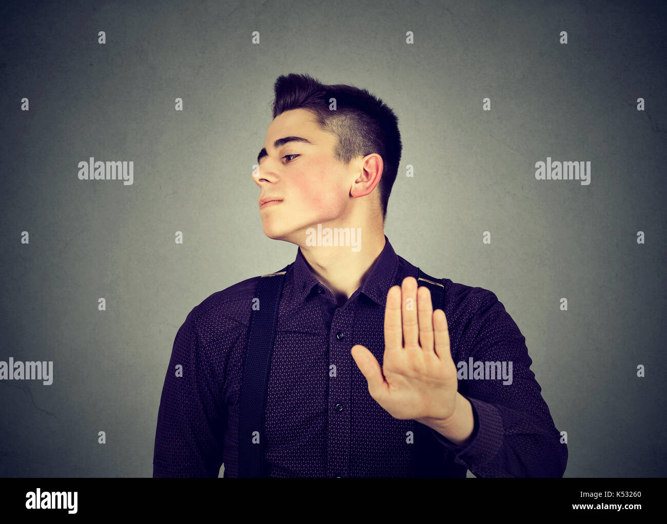 Closeup portrait angry man giving talk to hand gesture with palm outward isolated on gray wall background. Negative human emotion feeling body languag Stock Photo