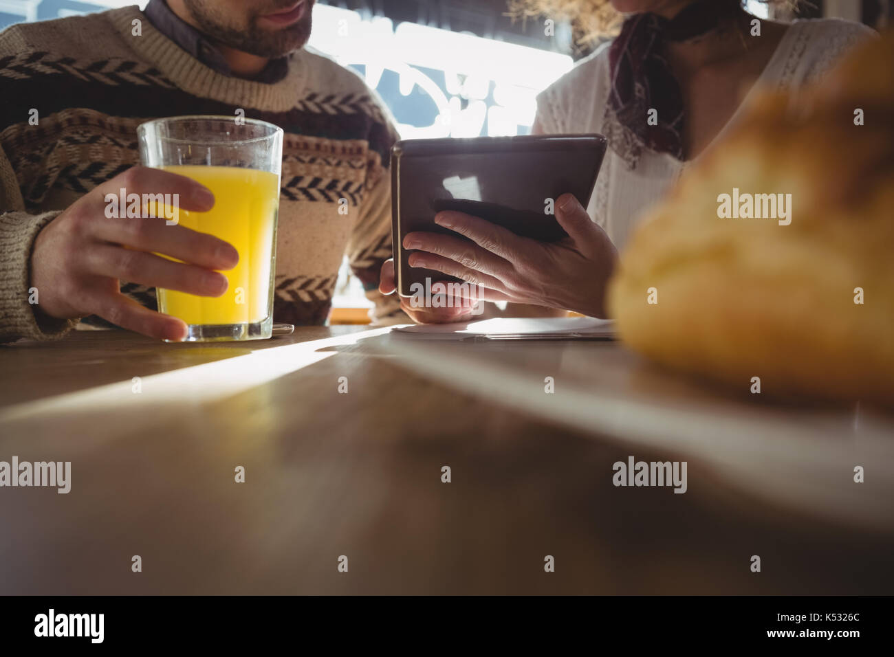 Mid section of woman with man using digital tablet at table in cafe Stock Photo