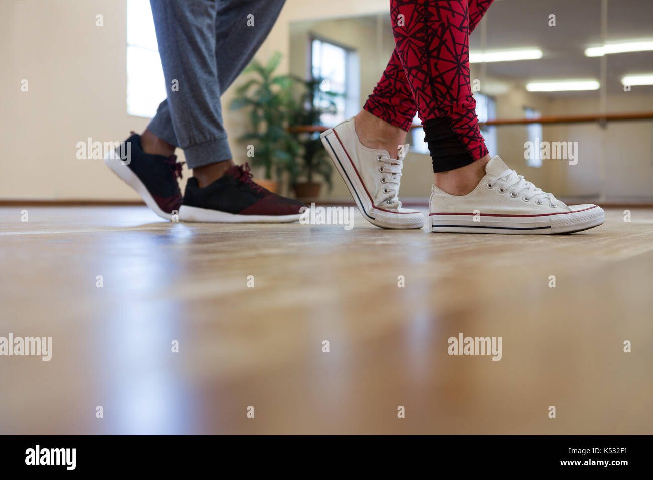 Low section of man with friend rehearsing dance on hardwood floor Stock