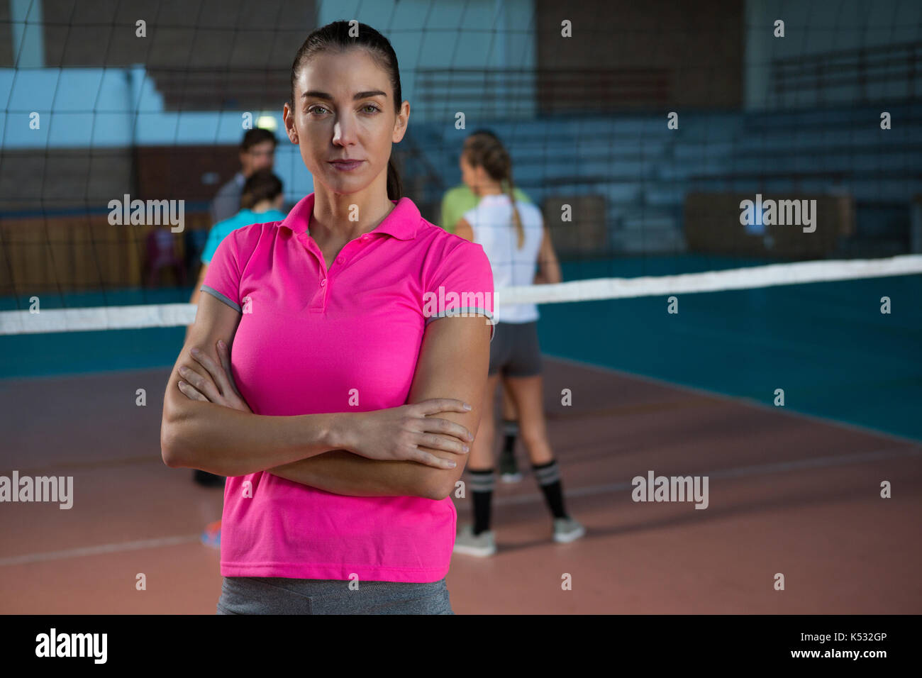 Portrait of female volleyball player with teammates playing in background at court Stock Photo