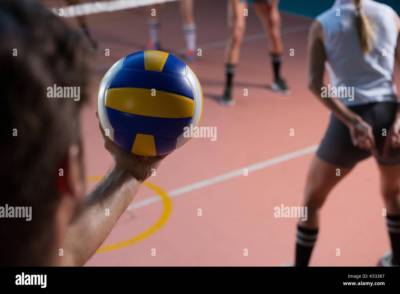 Cropped hand of player holding volleyball by female teammate at court Stock Photo