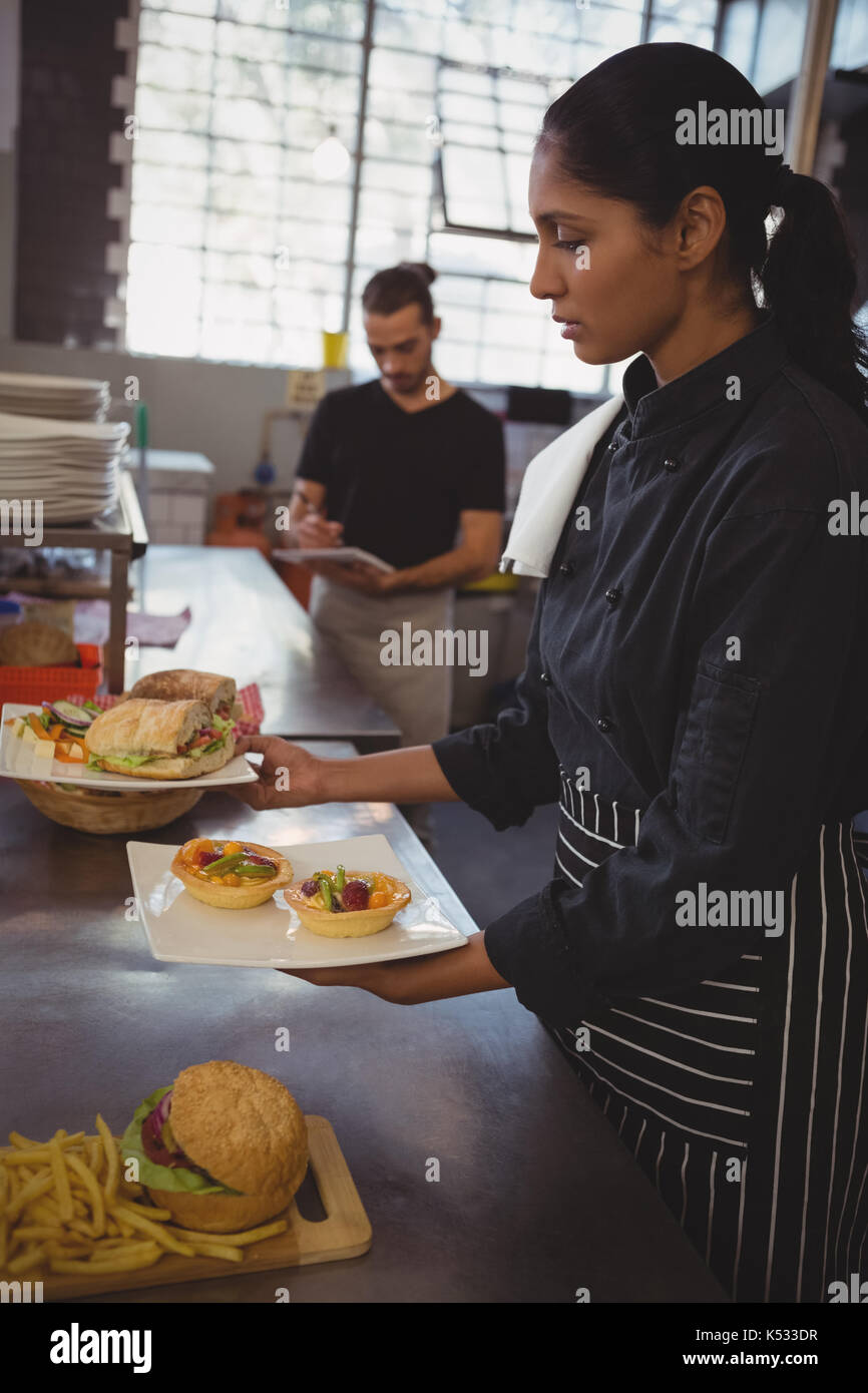 Young waitress holding plates with food at counter in cafe Stock Photo