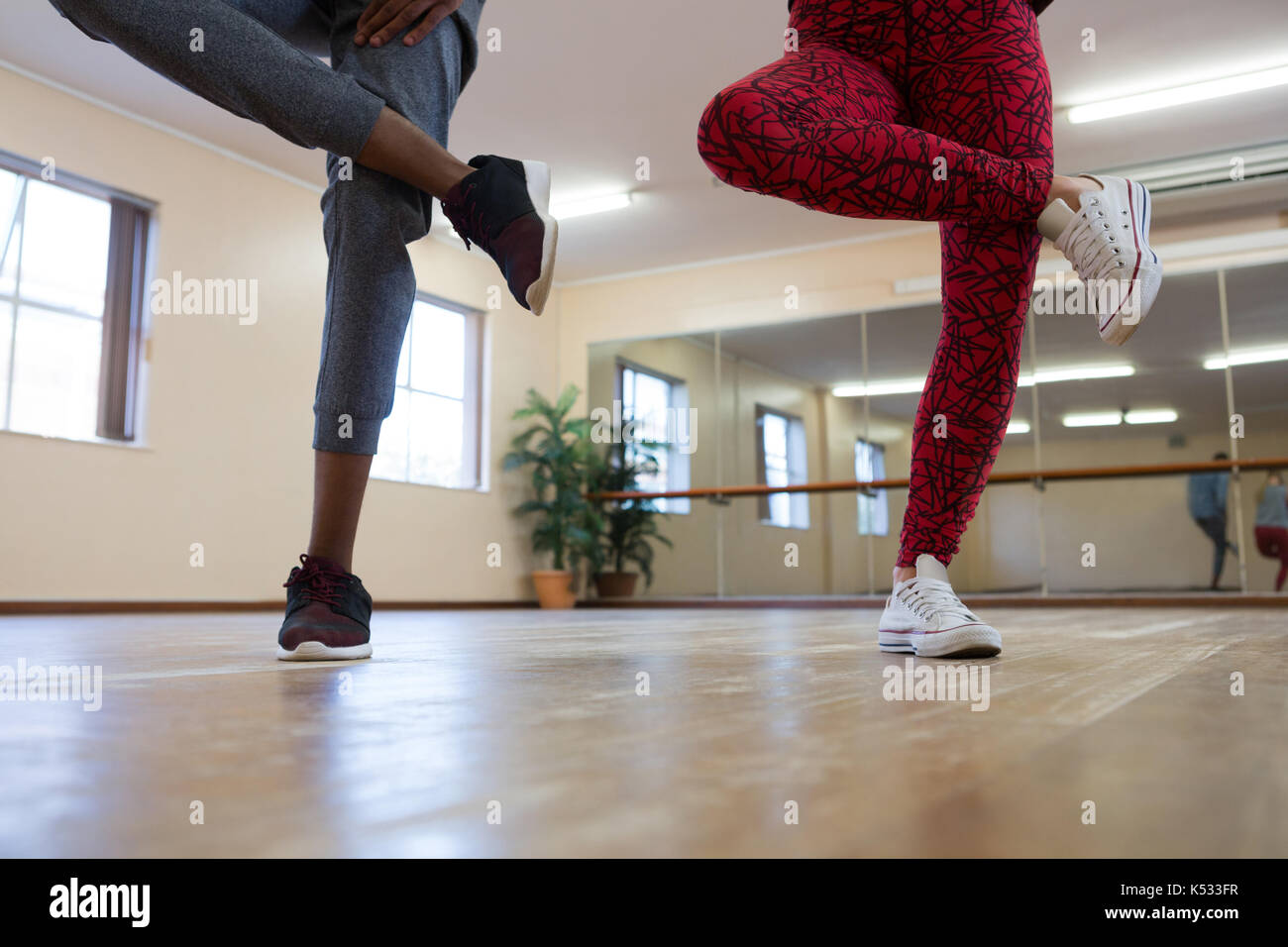Low section of young friends rehearsing dance on hardwood floor in