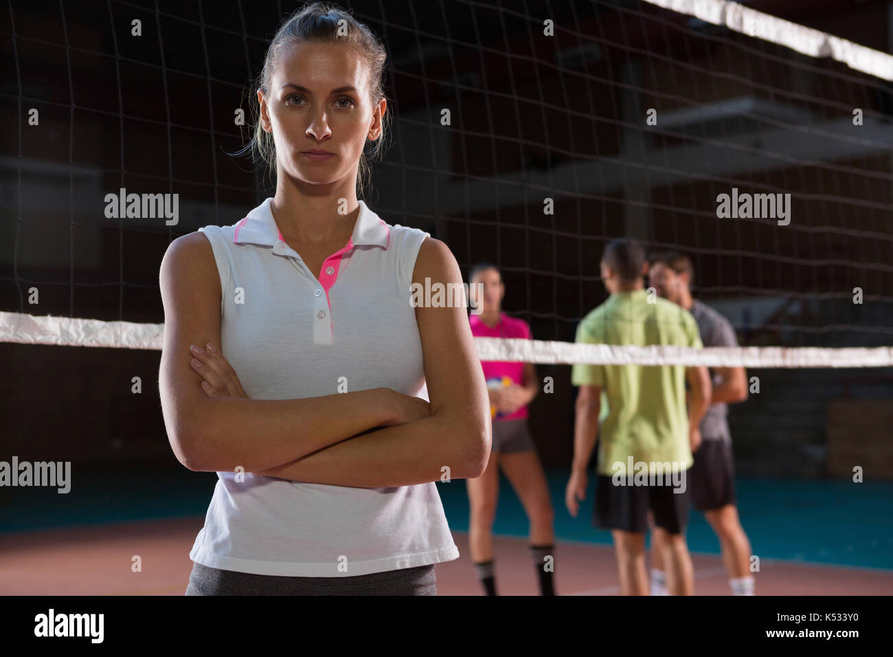 Portrait of confident female volleyball player with teammates in background at court Stock Photo