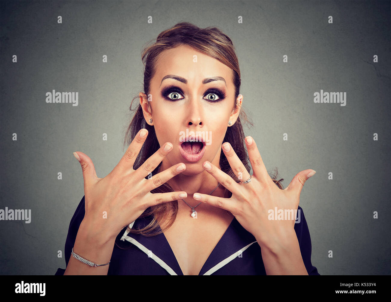 Amazed shocked woman looking at camera isolated on a gray background Stock Photo