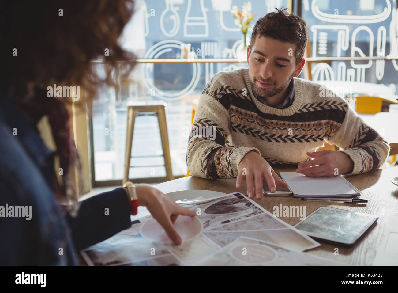 Young man with woman discussing over chart at table in cafe Stock Photo