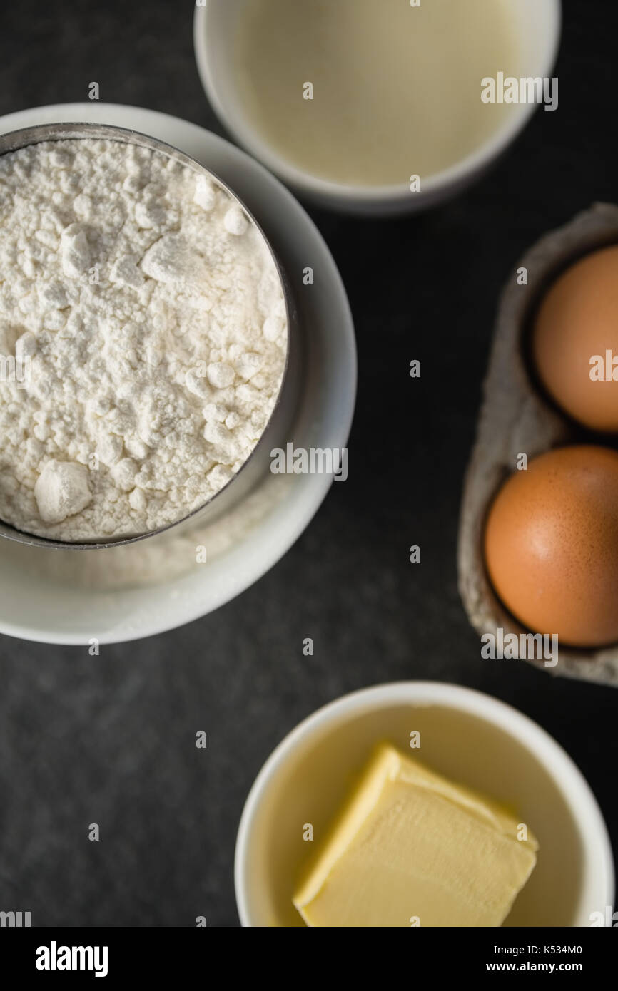 Overhead view of flour with butter and eggs on table Stock Photo