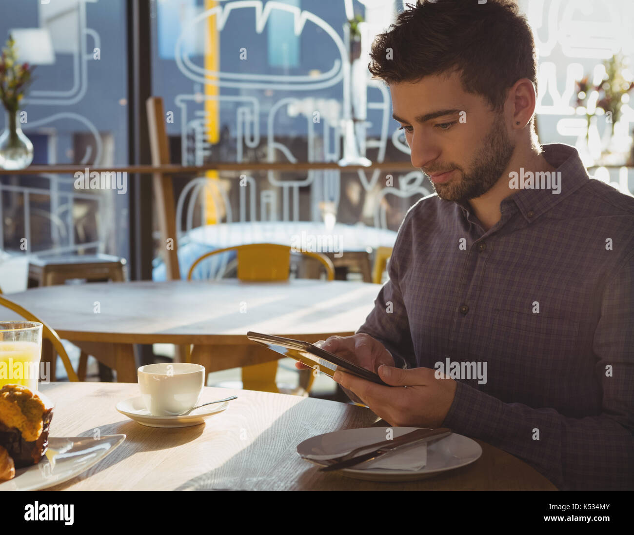 Young businessman using digital tablet while having breakfast in cafe Stock Photo