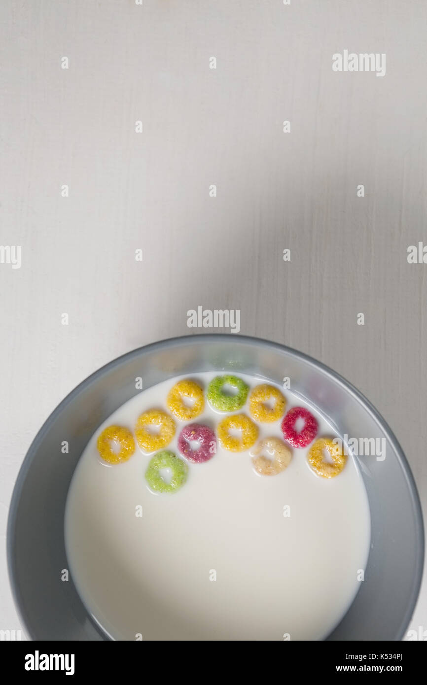 Overhead of milk bowl and cereal rings on white background Stock Photo