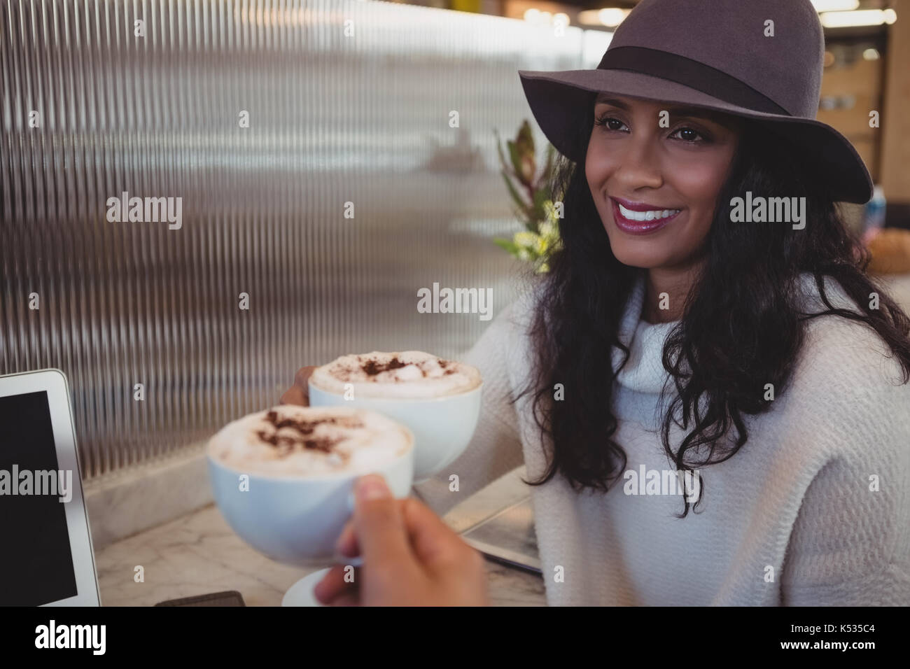 Cropped hand of man having coffee with smiling woman at counter in cafe Stock Photo