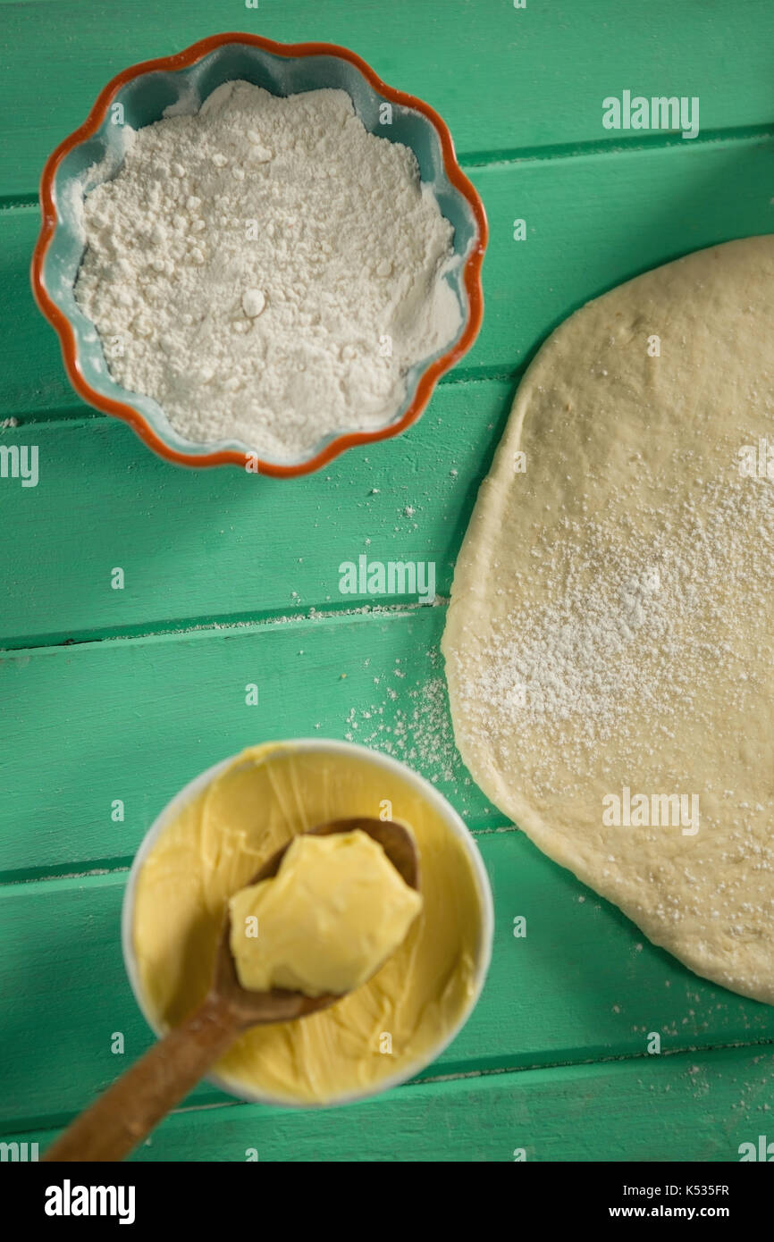 Overhead view of rolled dough by butter and flour in bowl on table Stock Photo