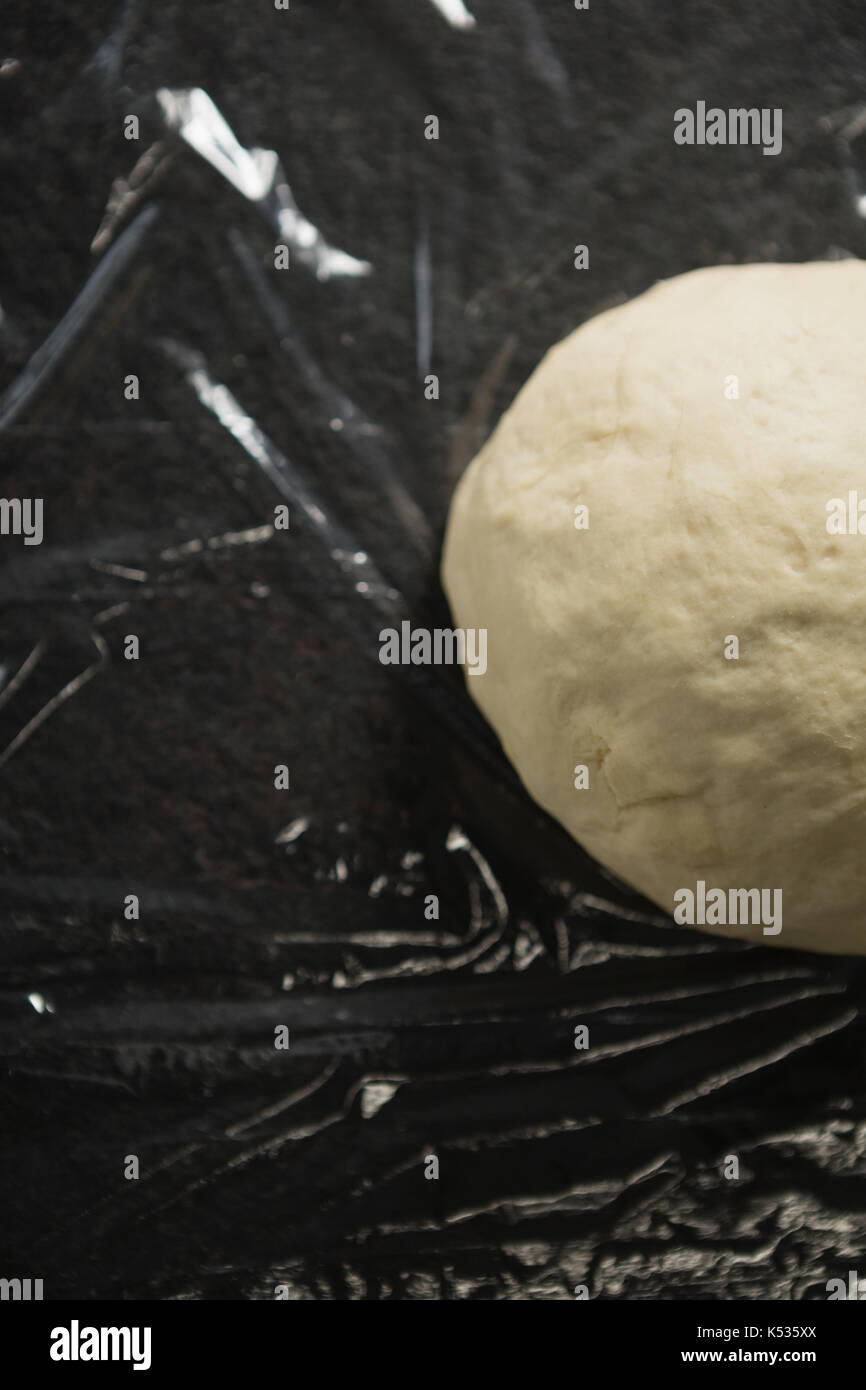 Overhead view of dough on plastic wrap at table Stock Photo Alamy