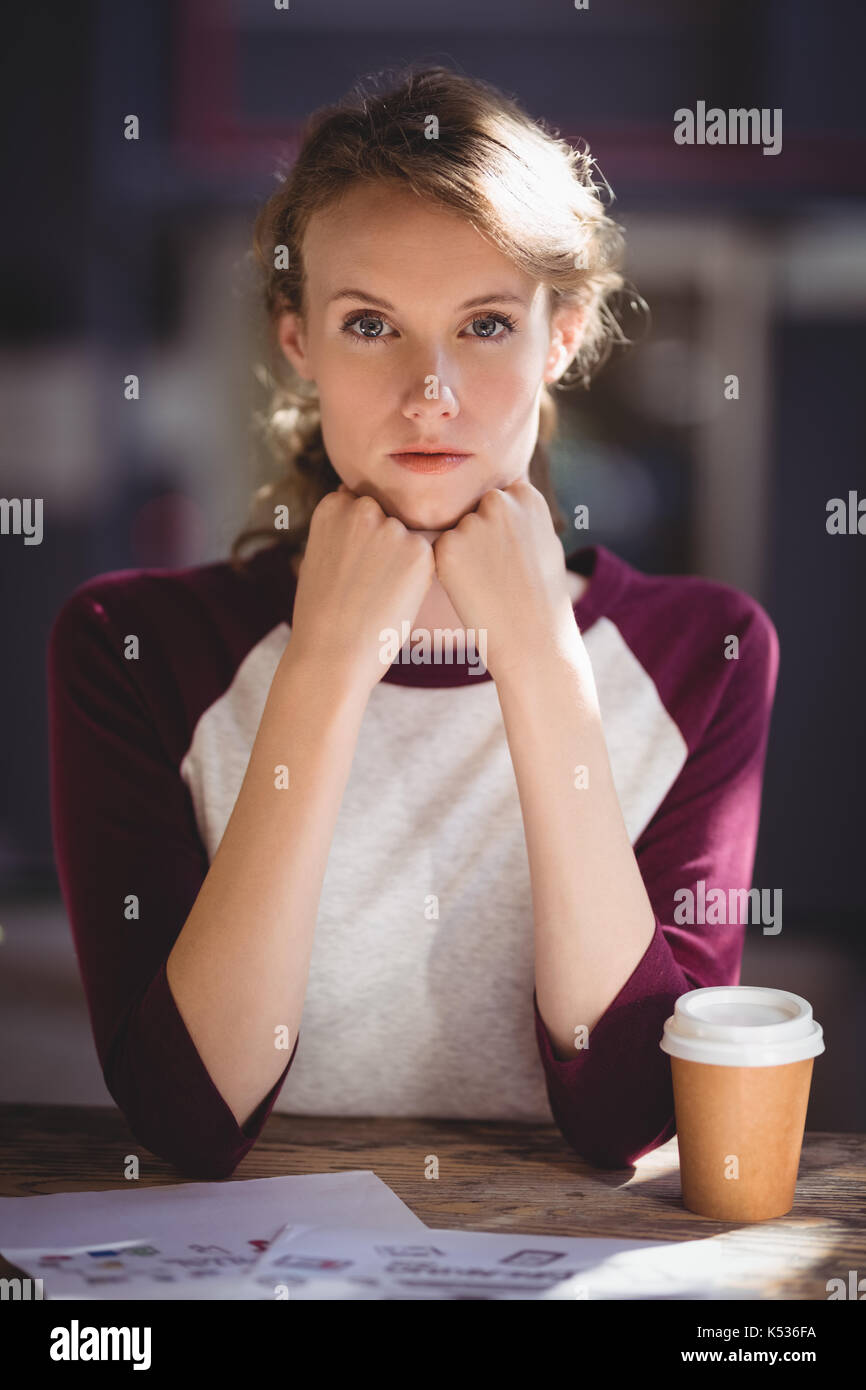Portrait of confident young female design professional sitting at table in coffee shop Stock Photo