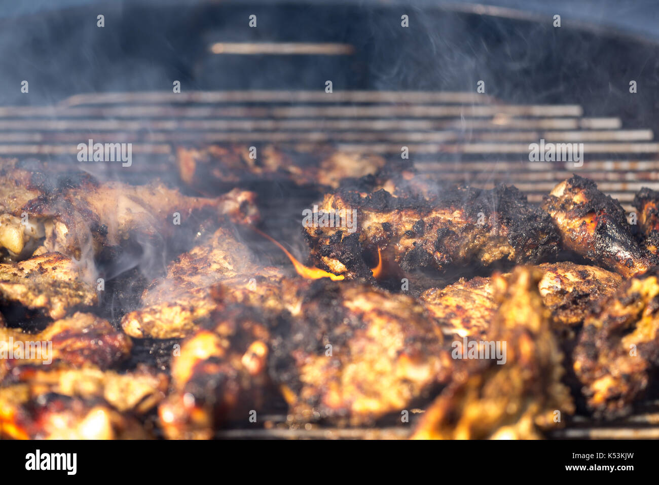 Grilling traditional Jamaican spicy jerk chicken with over wood fire