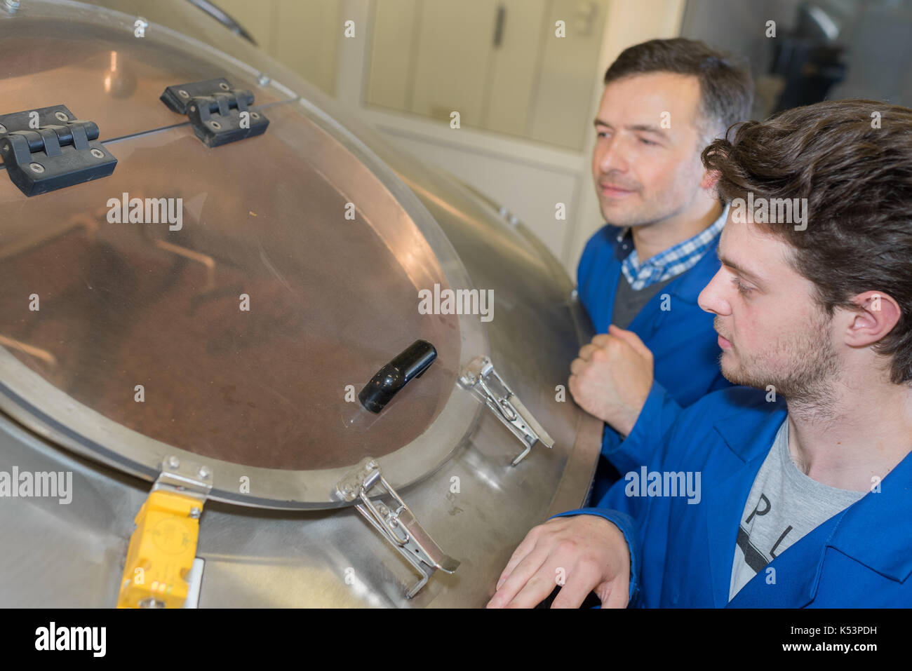 two workers at plant checking parameters of pressure Stock Photo