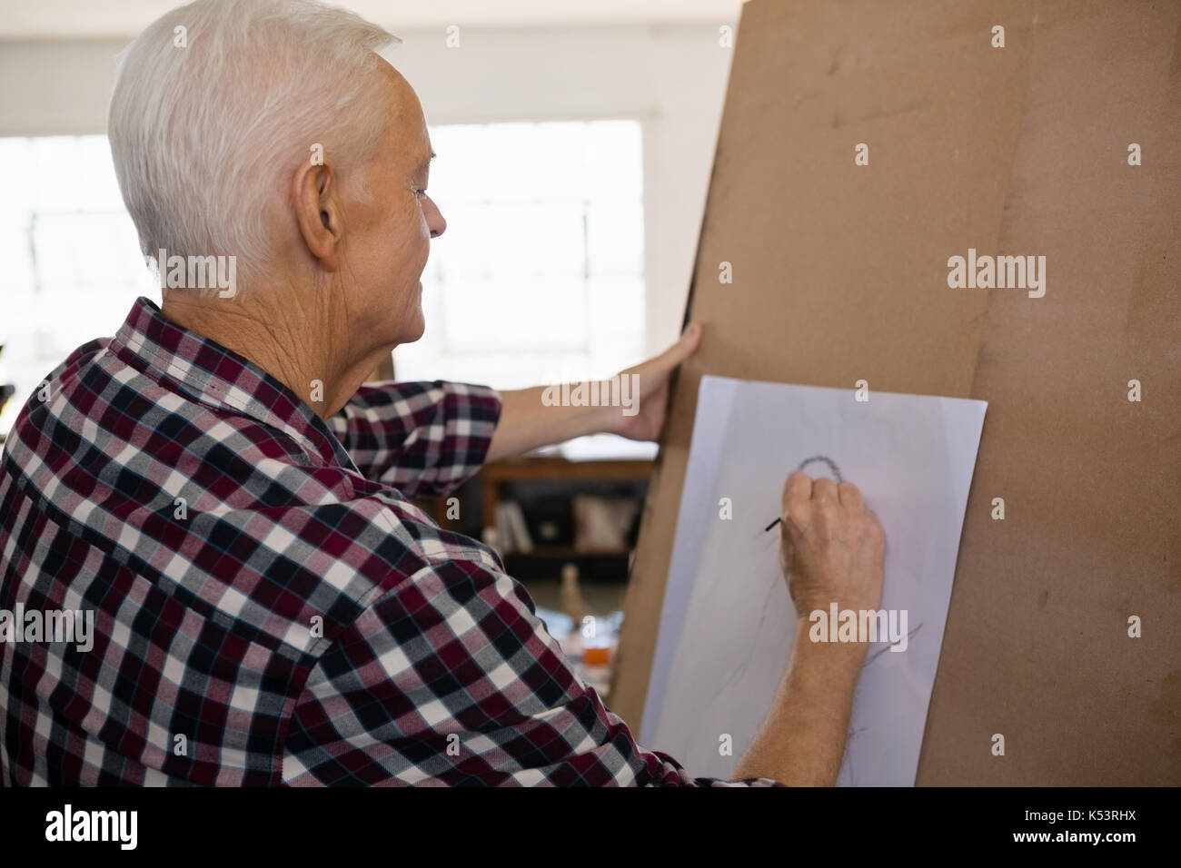 Side view of senior man painting on paper in art class Stock Photo - Alamy