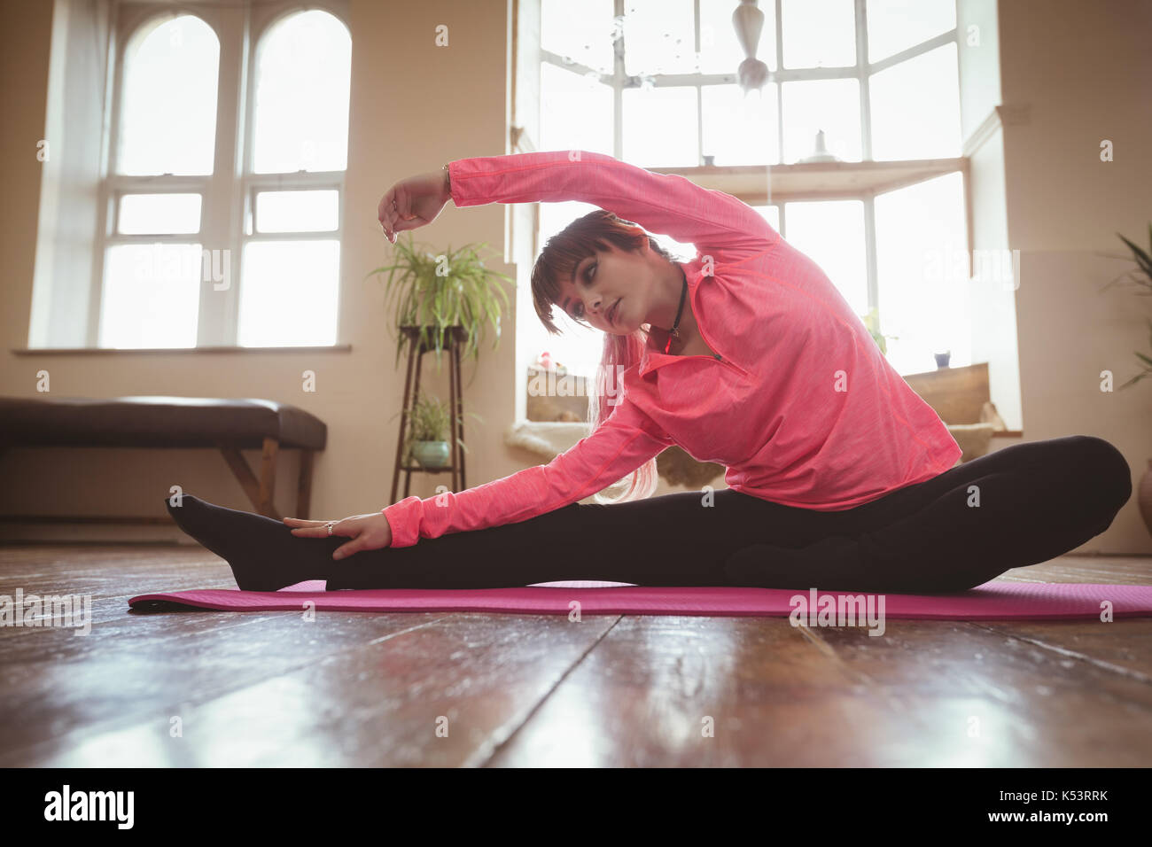 Young woman stretching while doing yoga on exercise mat at studio Stock Photo