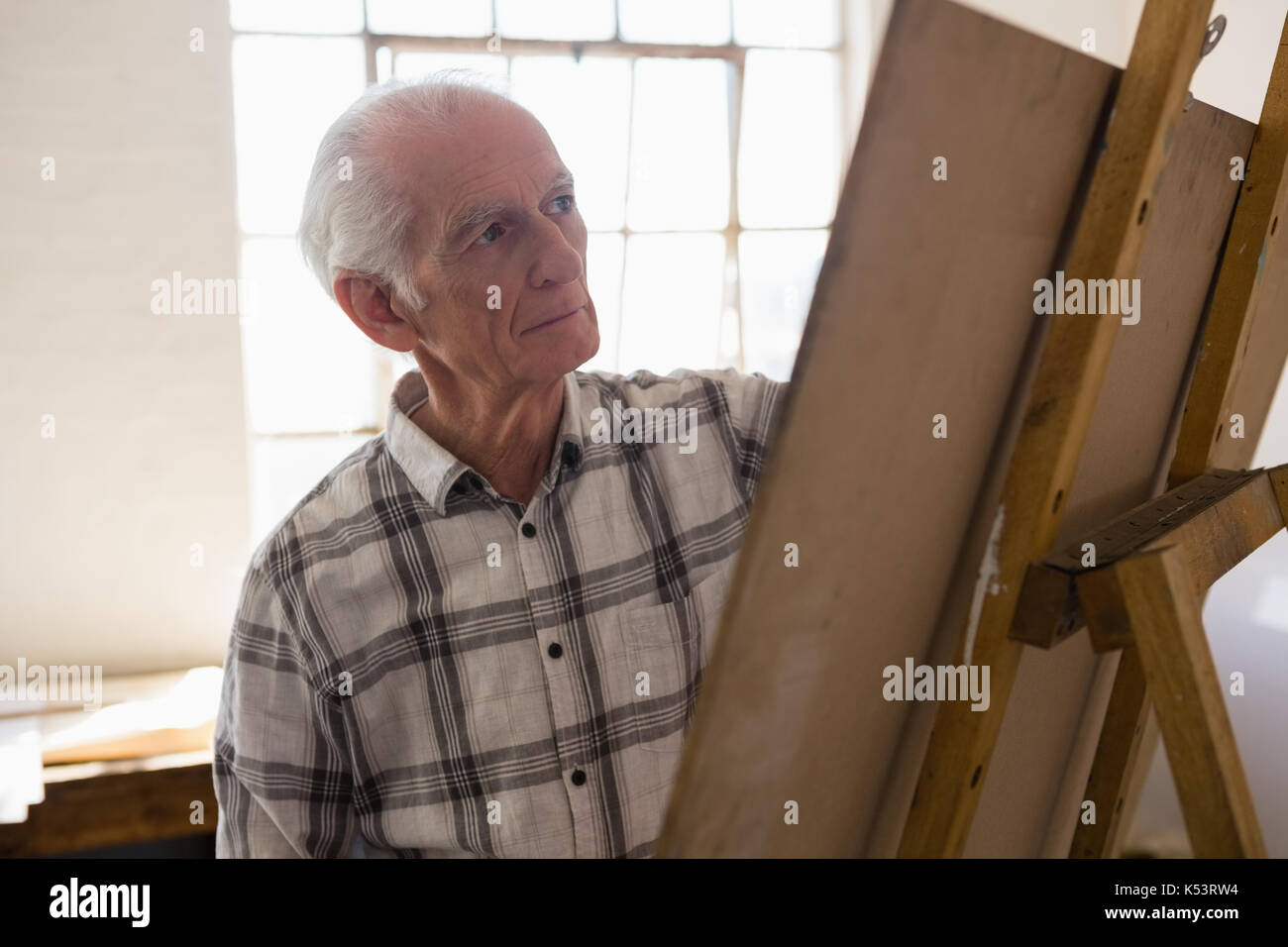 Senior man painting on easel in art class Stock Photo - Alamy