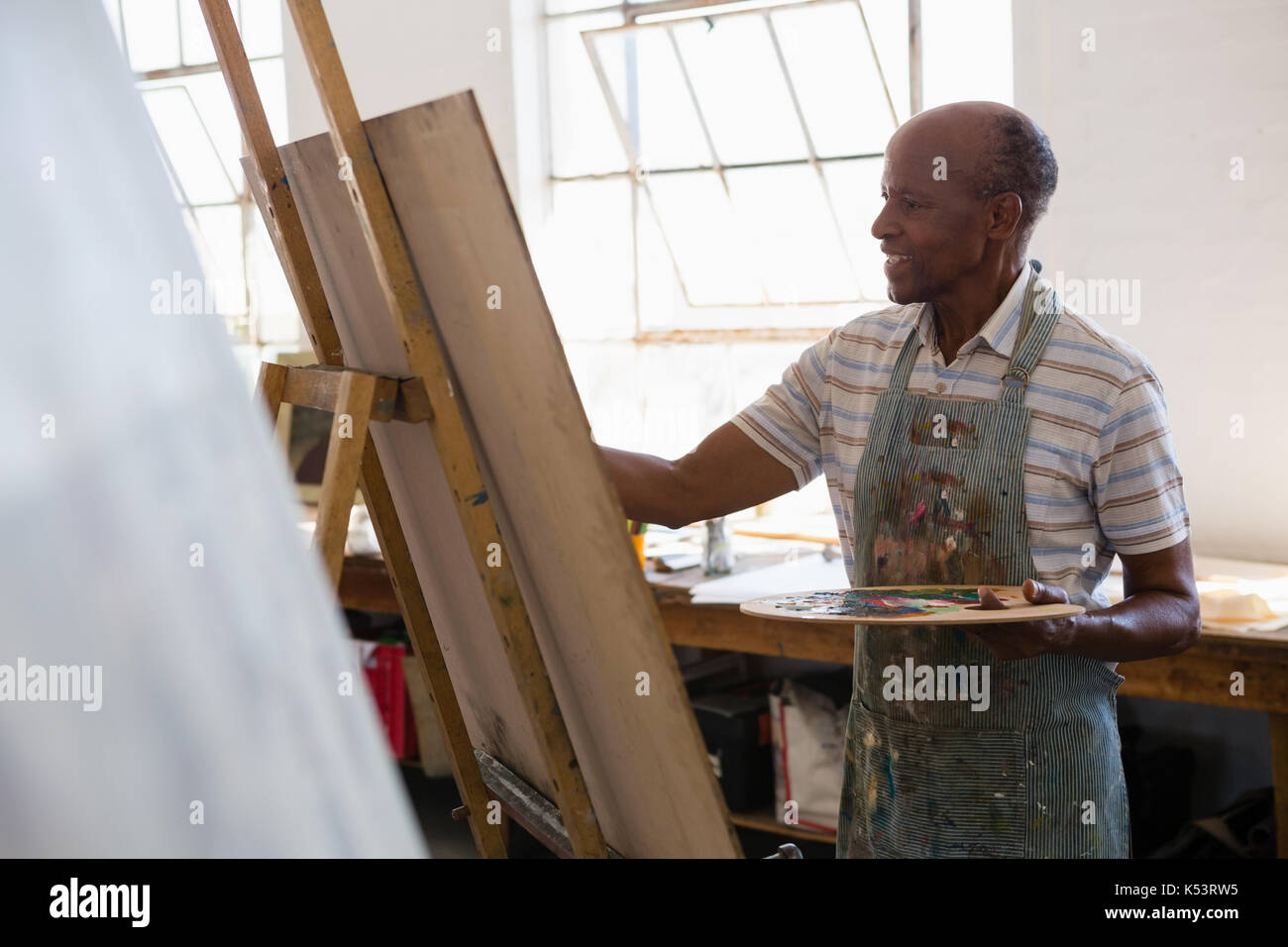 Senior man painting while standing in art class Stock Photo