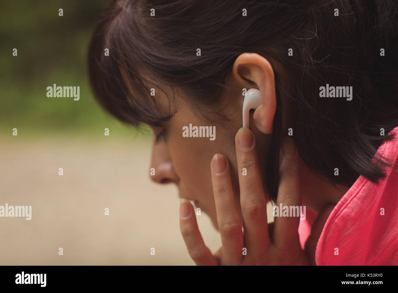 Close-up of woman listening music on headphones in forest Stock Photo