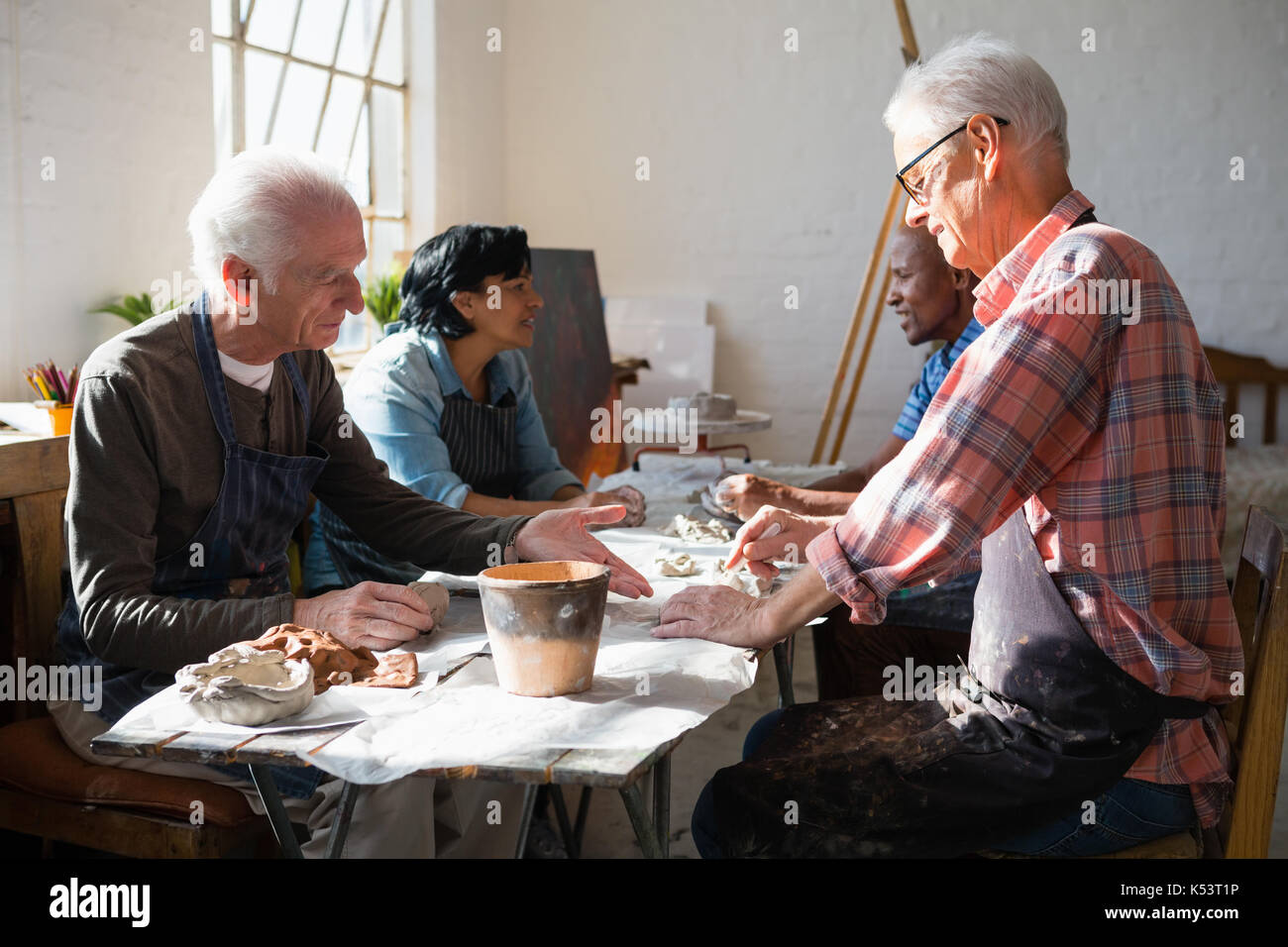 Senior people making clay products while sitting at table in art class Stock Photo