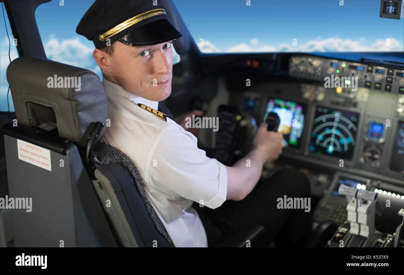 Portrait of confident young male pilot flying airplane while sitting on seat in cockpit Stock Photo