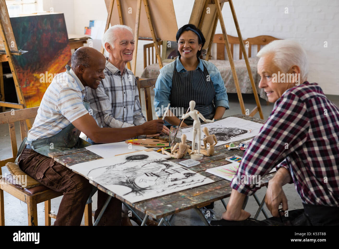 Happy senior friends talking at table in art class Stock Photo