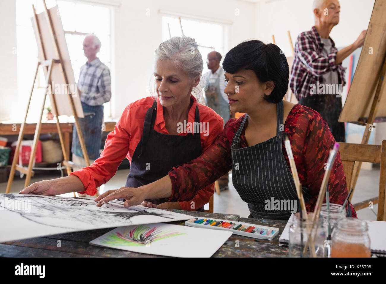 Senior woman gesturing while assisting friend in art class Stock Photo ...