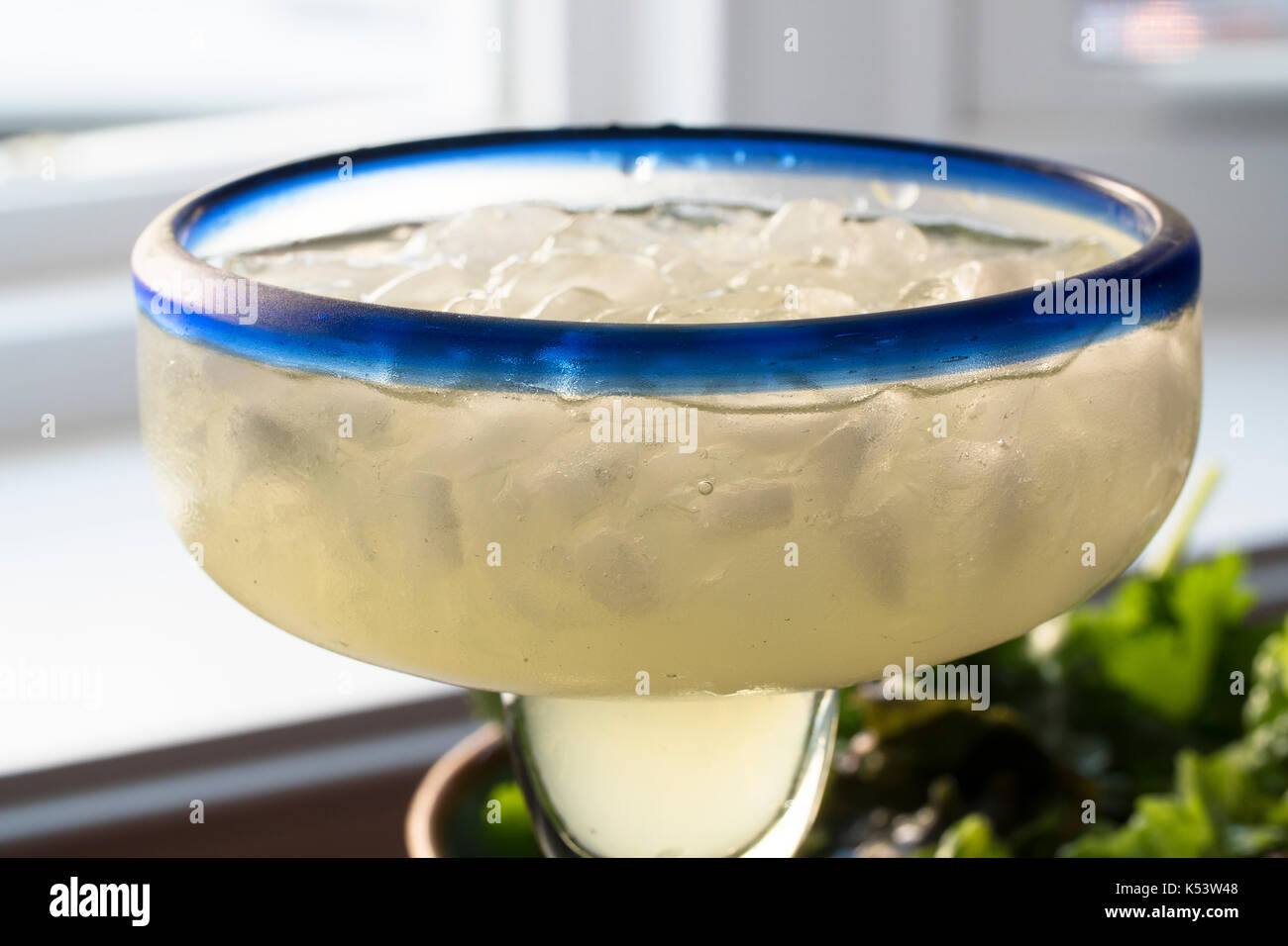 Close up of margarita on ice in glass with blue rim. Stock Photo