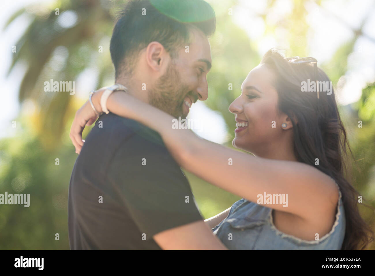 Profile portrait of happy couple in love embracing and looking at each other Stock Photo