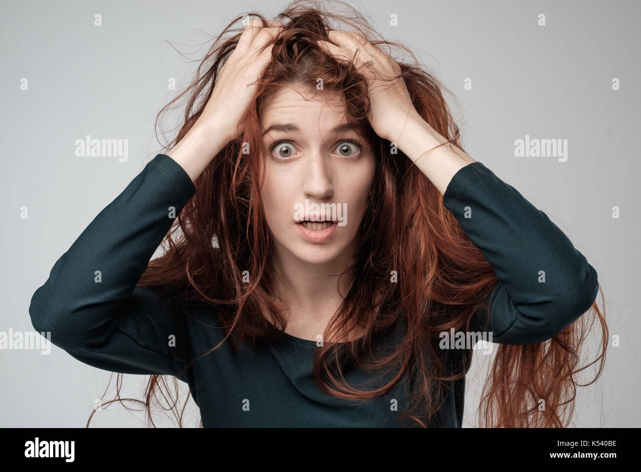 Pretty caucasian woman trying to comb hair. Shocked emotion on face Stock Photo
