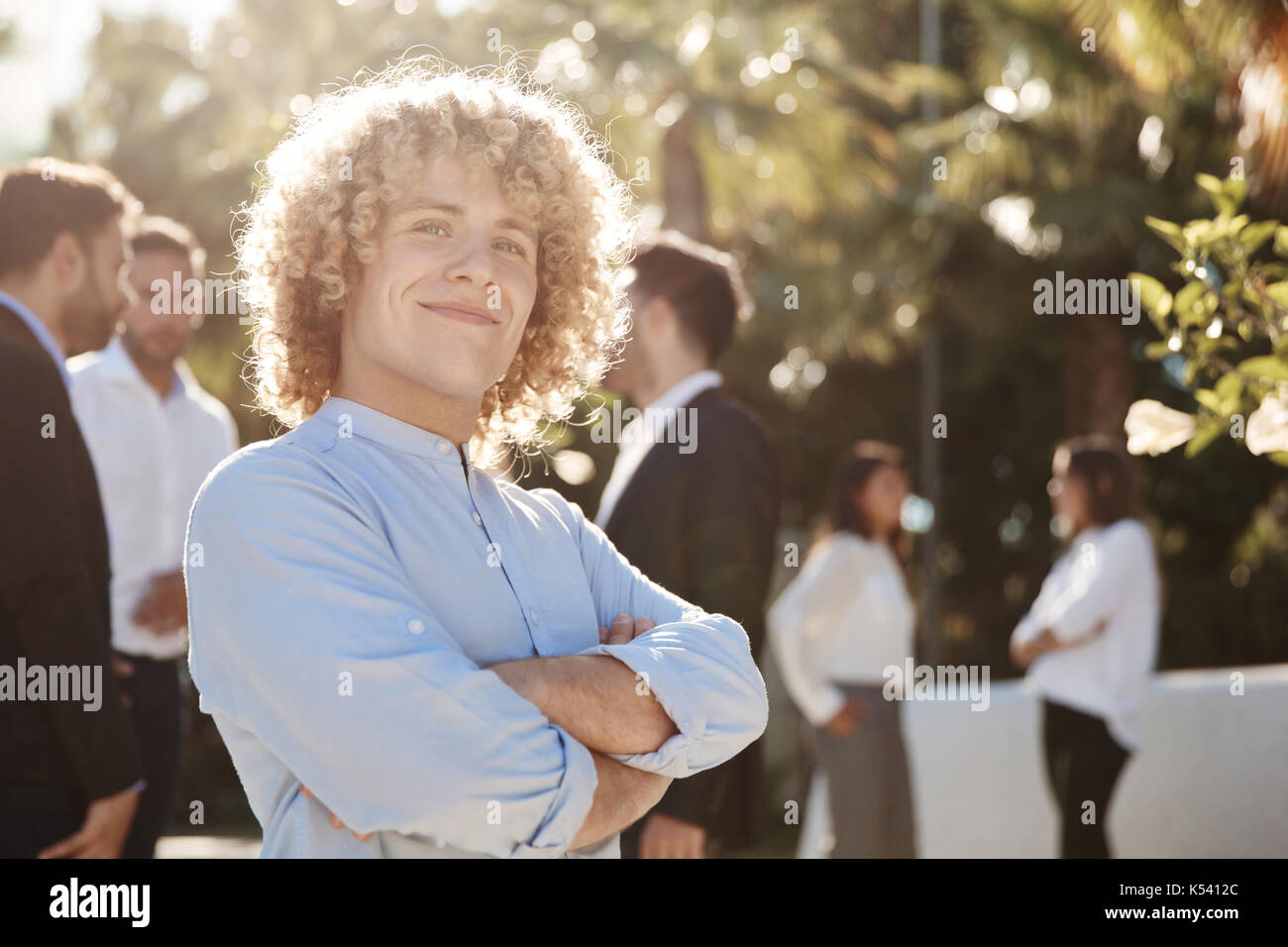 Front portrait of happy businessman standing with crossed arms outside ...