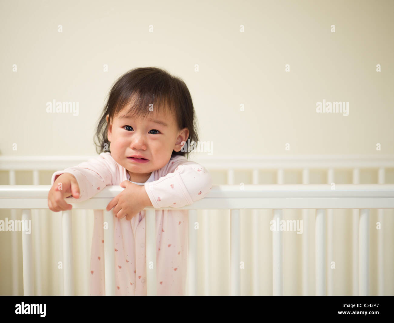 Baby girl crying in cot bed Stock Photo Alamy