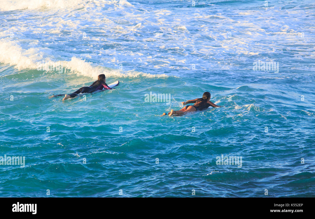 Teenage girls surfing at sunrise at Redgate Beach in Margaret River. Western Australia Stock Photo