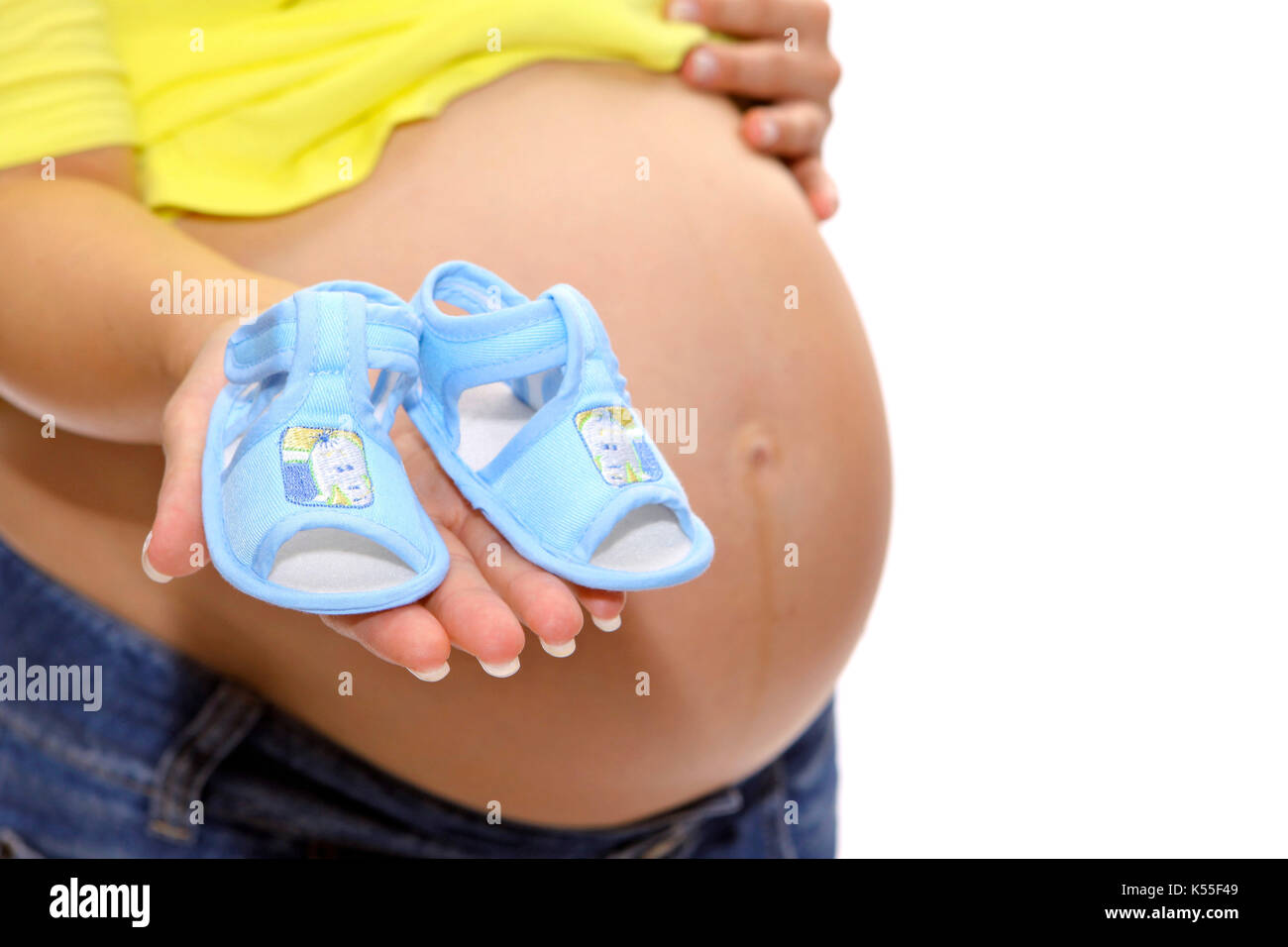 Pregnant woman with baby bump shows baby shoes Stock Photo