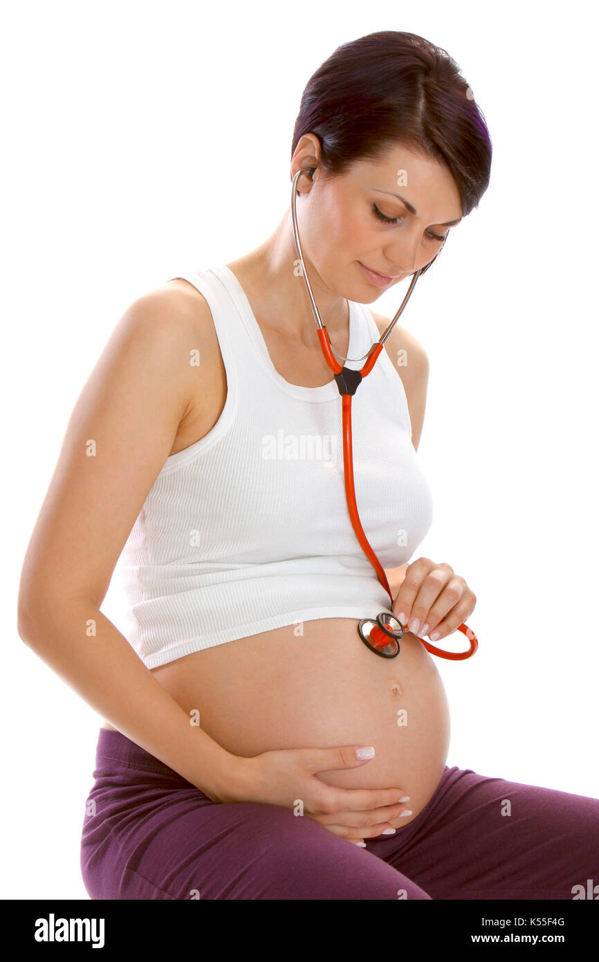 Pregnant woman listens with a stethoscope at her baby belly Stock Photo